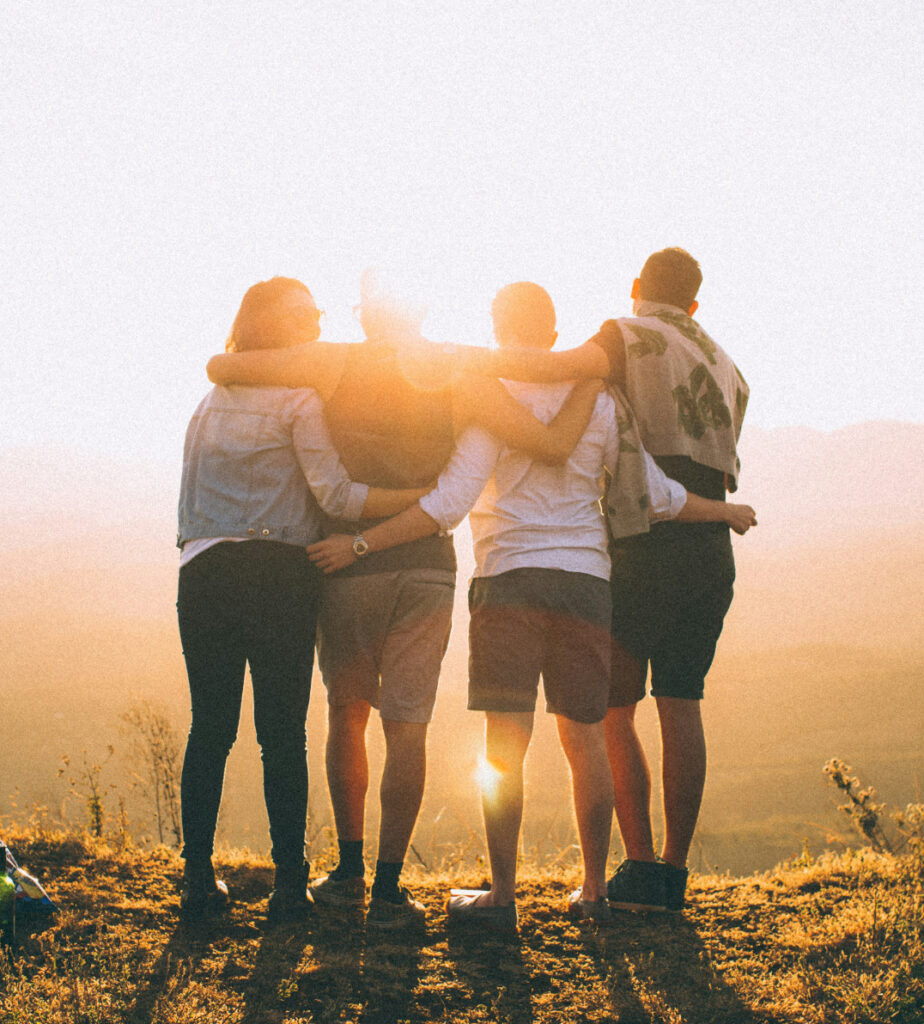 4 people hugging in front of a sunset